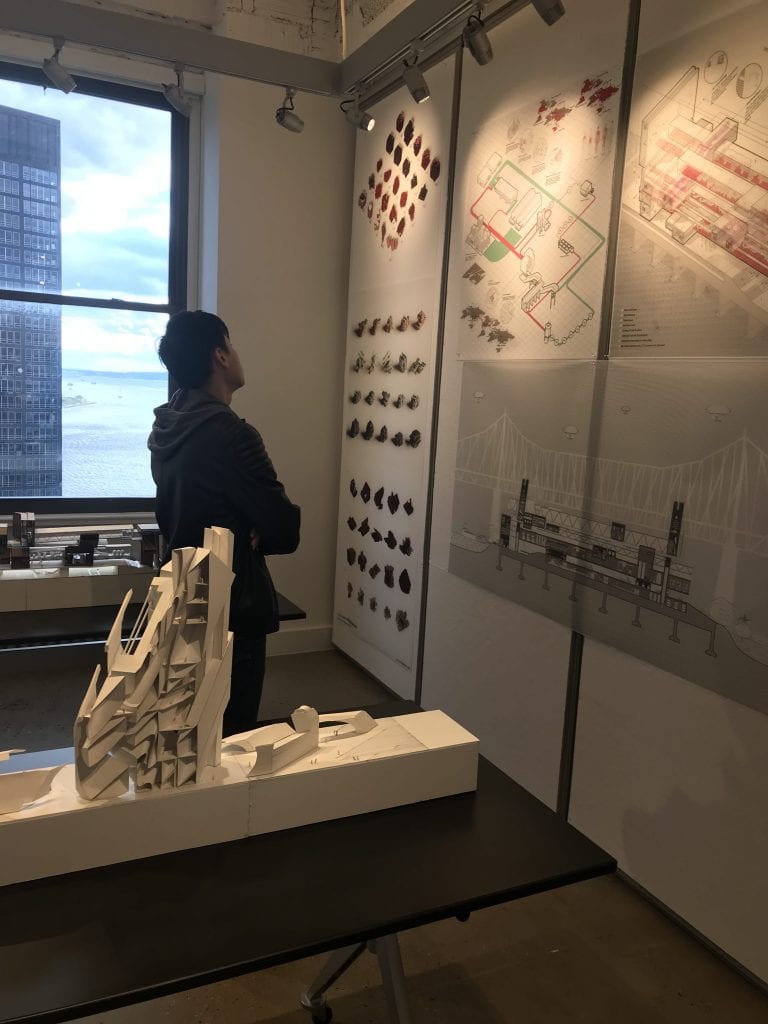 Person looking at three panels depicting architectural drawings.