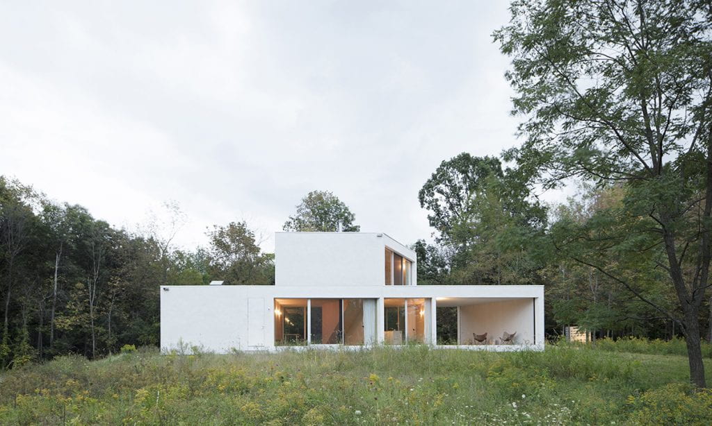 White geometric two story building in a landscape.