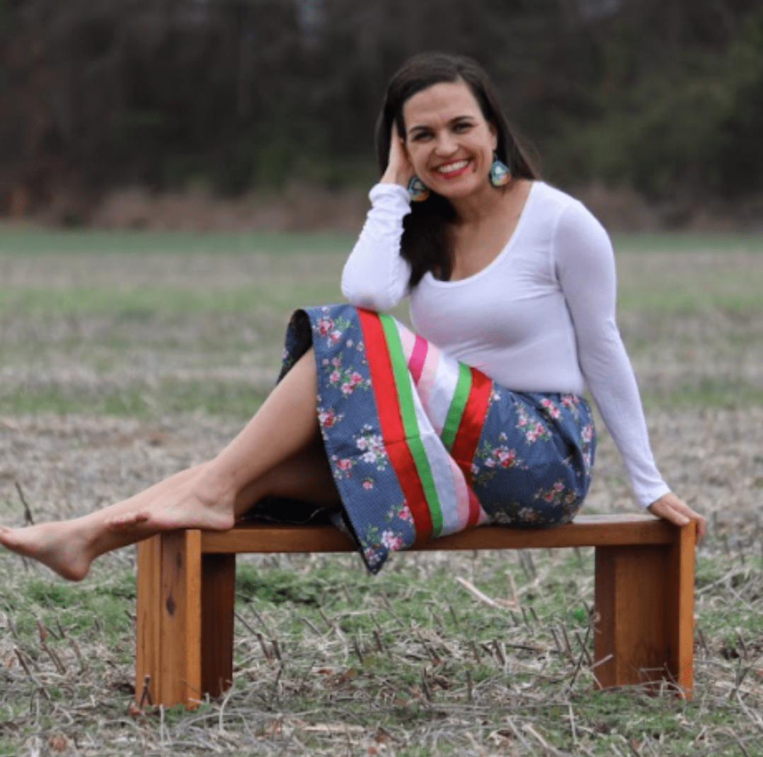 Woman sitting on a bench in a colorful skirt.