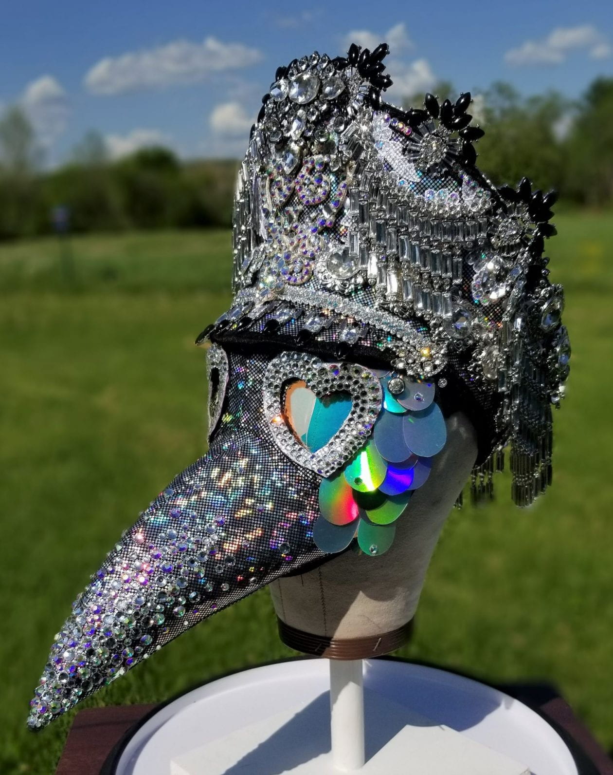 A metallic mask and hat on a head form.