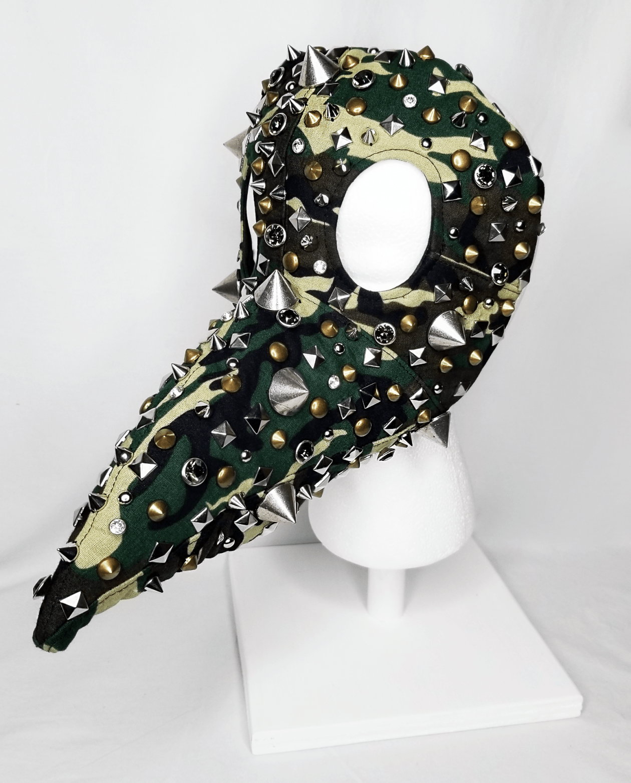 A beaked mask in camouflage covered in studs