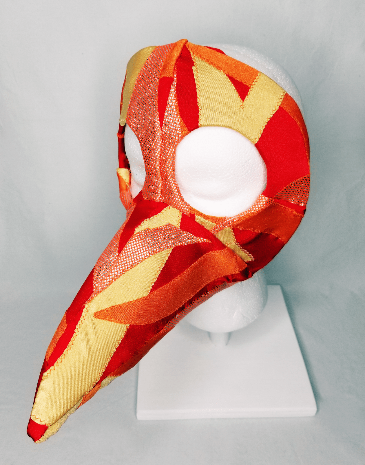 A beaked mask in orange, red, and yellow
