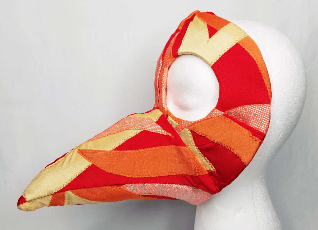 A beaked mask in red, orange, and yellow.