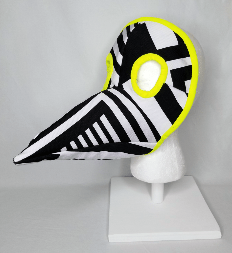A beaked face mask in black and white stripes with neon yellow binding.