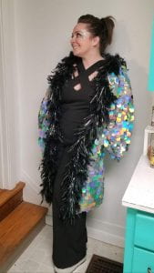 A woman wearing a sparkly long coat with feathers