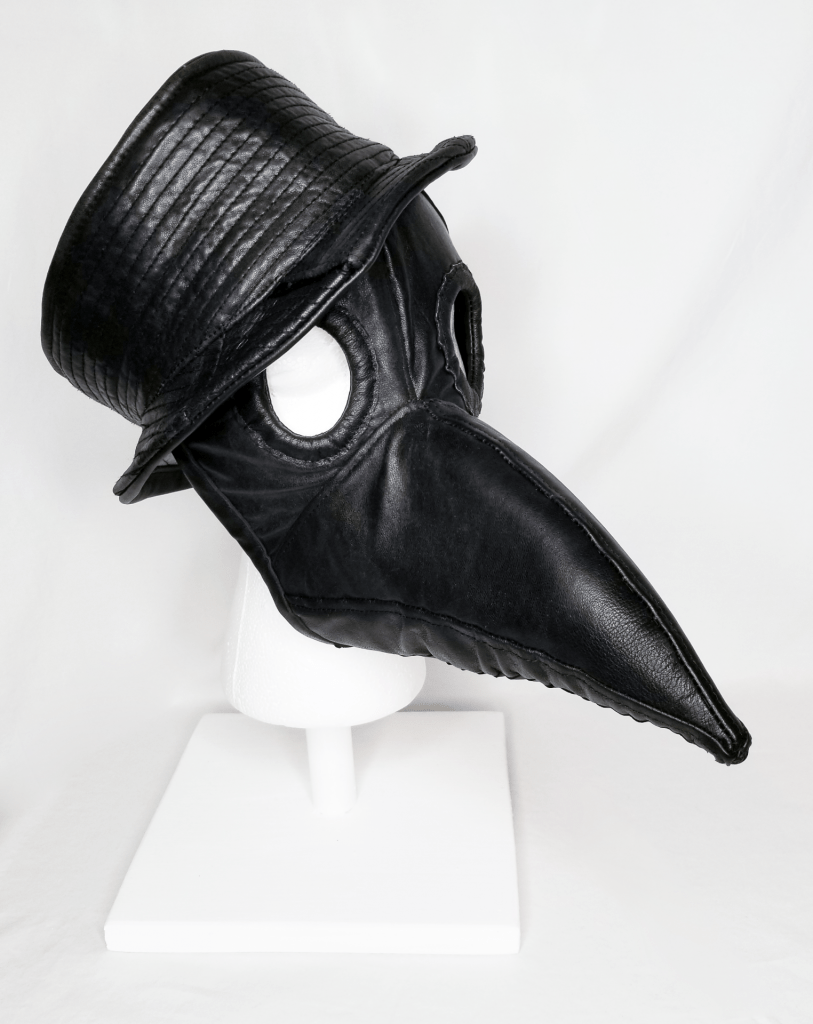 A black leather beaked mask with hat on a head form