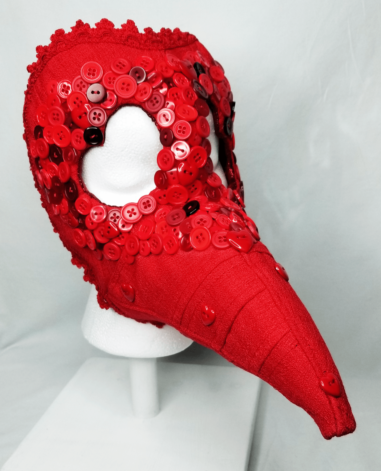 A red beaked mask with button embellishments