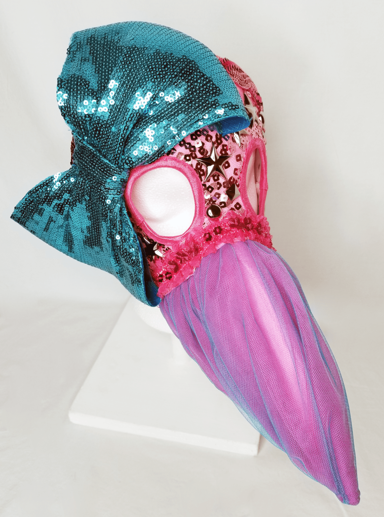 A pink beaked mask with a blue sequin bow