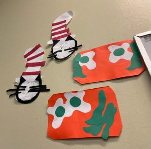 This image shows two student-made paper cut out of the Cat in the Hat eating green eggs and ham.