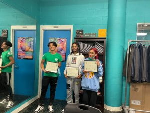 Three teens stand side by side presenting certificates of completion