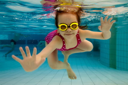 Little girl swimming underwater and smiling.