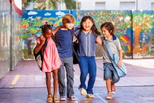 Schoolchildren embracing happy. Multi cultural racial classroom.