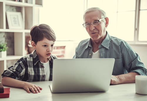 Grandfather and grandson using a laptop for remote learning.
