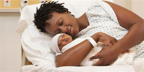 Mother with newborn baby in hospital bed.