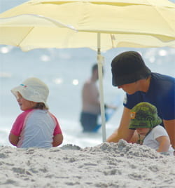 Dad with young children under an umbrella at the beach