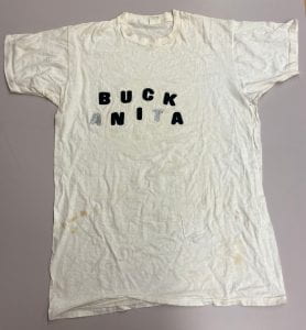T-shirt that says "Buck Anita." The letters are black save for the first "A" and "T" in Anita, which are a glittery silver.