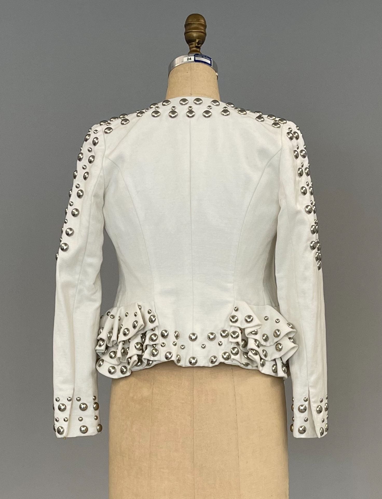 Back of white jacket with round decorative metal studs. 