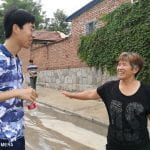 student talks to a resident of a village on the street
