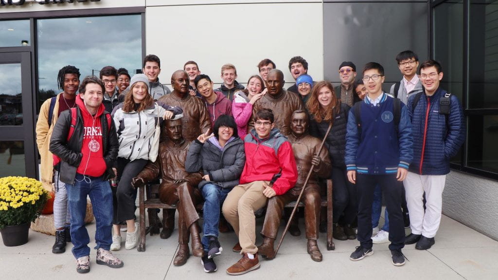 group of people posing with a statue
