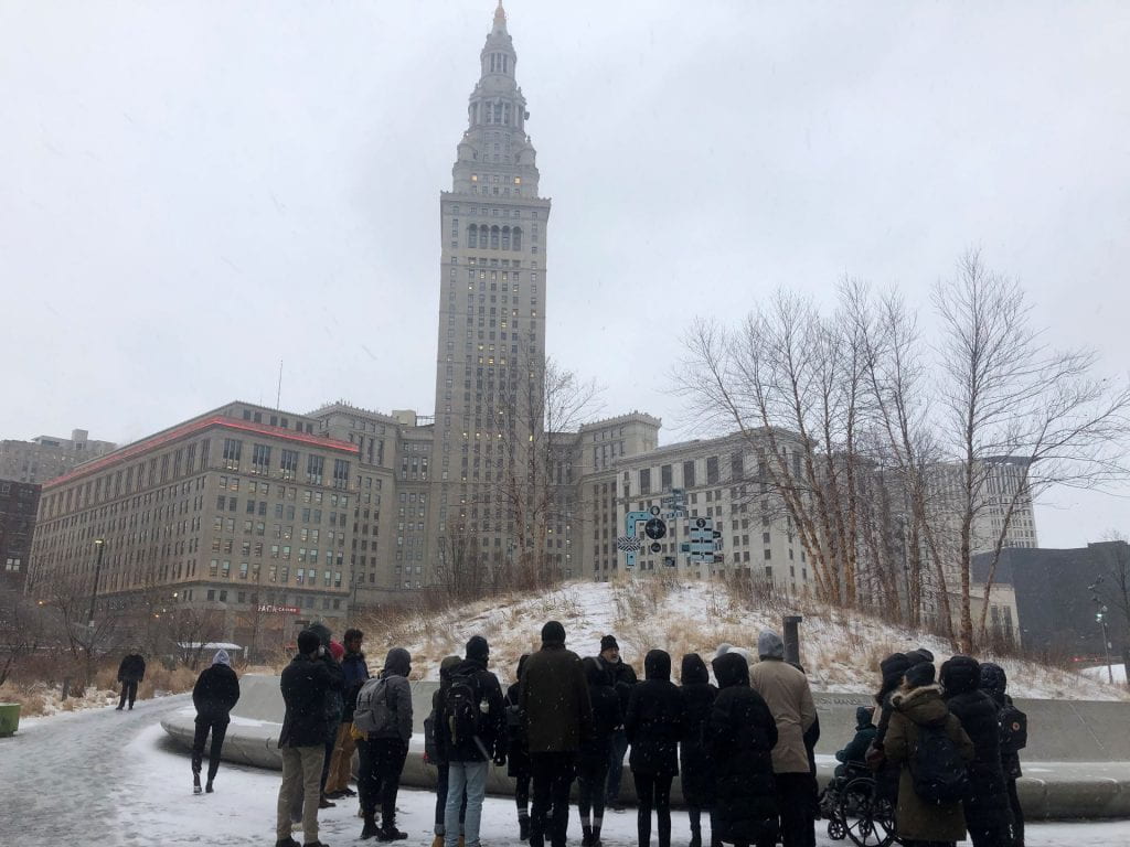 group of people standing outside a tall building, bundled up in the winter