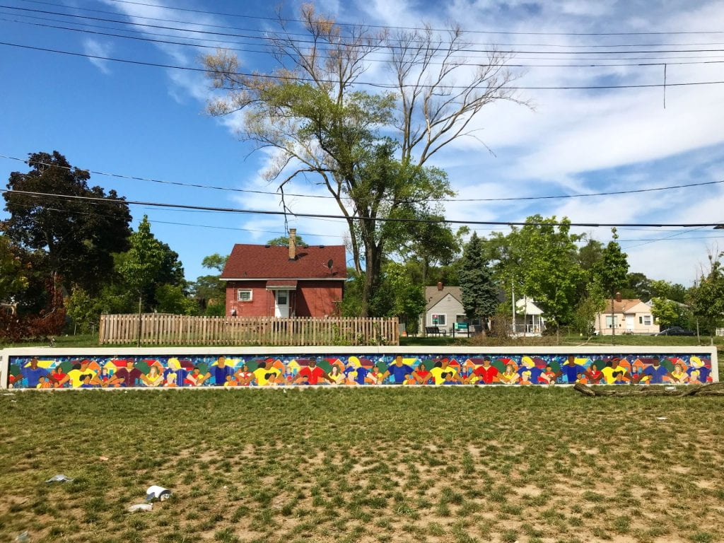 photo of art mural above lawn with trees and houses in background