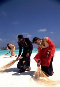 Maldivian female staff sweeping the beach. Dave Jackson. 2006