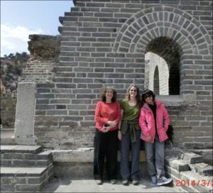 three women in casual clothes stand in front of a stone archway