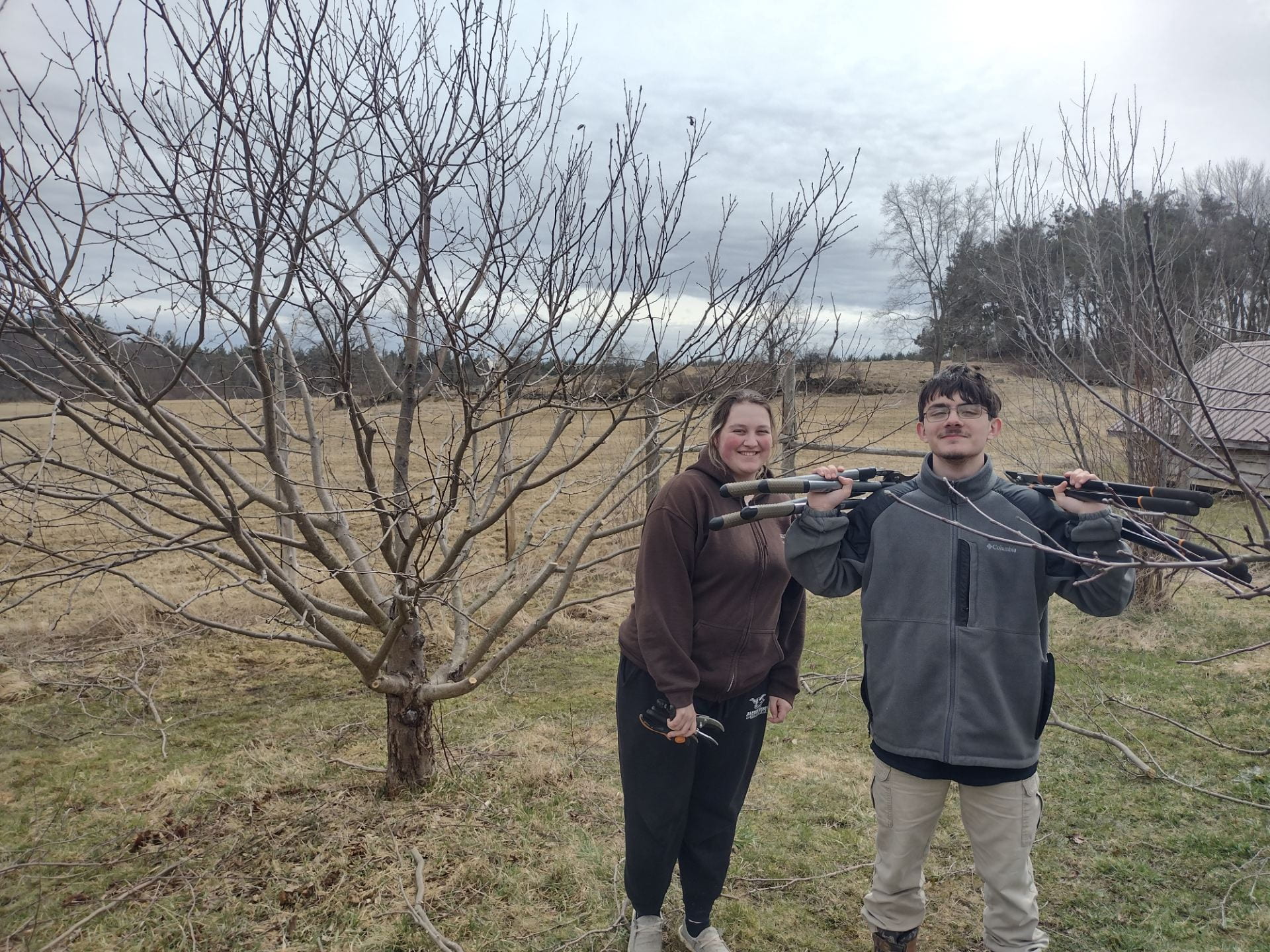 High school students pose in front of an apple tree after pruning this spring