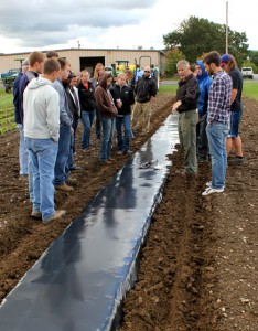 Students inspect newly laid plastic mulch.