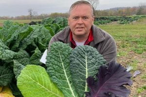 Phillip Griffiths with several of his new kale varieties showing different colors and textures from green to red and smooth to crinkled.
