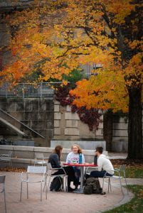 students outside mann library with fall foliage in the background
