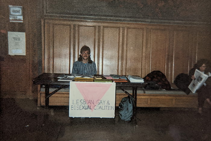 A member of the Lesbian, Gay, & Bisexual Coalition (1990s) tables in the foyer of Willard Straight Hall to spread awareness about the organization, AIDS prevention and testing.