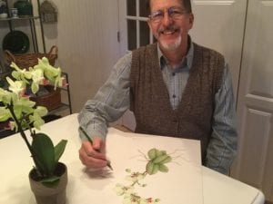 Doug pretends to work on a botanical drawing or the orchid sitting on the table in front of him