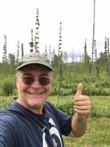 Joe giving a thumbs up standing in front of a hop yard