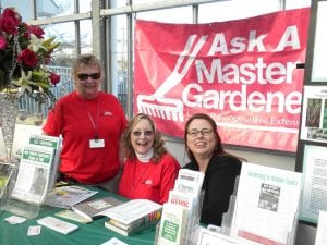 Three Master Gardener Volunteers staff an "Ask a Master Gardener Table" 
