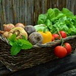 Wicker basket full of lettuce, tomatoes, peppers, beets, turnips,onions and a sprig of mint