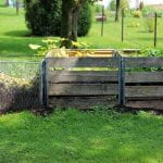 Three large compost bins, one made of wire fencing and two made of pallets