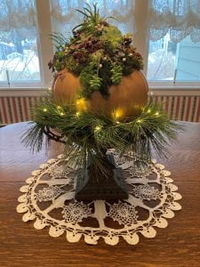 Pumpkin covered with succulents surrounded by pine branches and lights