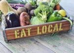 Wooden crate stenciled with Eat Local, filled with produce.