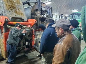Supervisor explaining how to properly maintain a skid steer.
