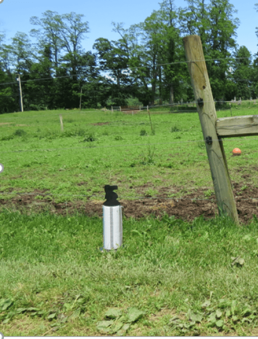  photo shows a device similar in shape to a large flashlight and suspended outdoors to draw flies away from livestock
