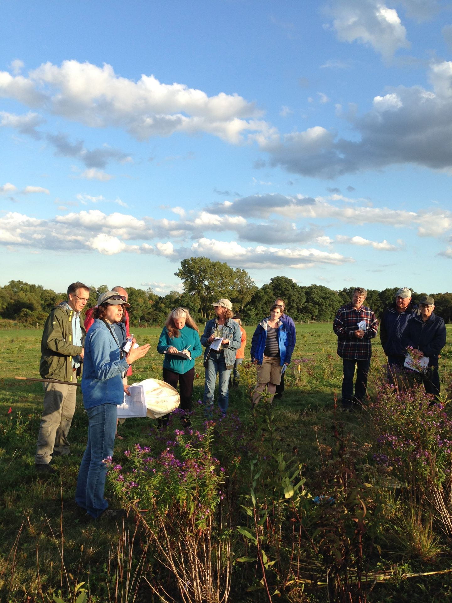photo shows six guests and two speakers from the IPM program standing near one of the habitat plots