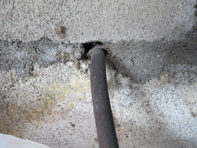 photo shows a gap in a cement wall around a utility pipe.