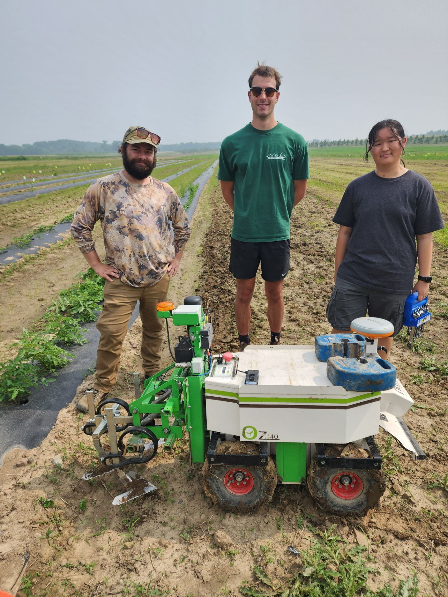 Three people and robot in field