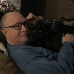 Steve Harris, '76 alumnus sitting on a couch with his cat