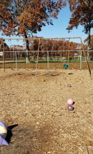 A mulched playground with swingset and toy balls on the ground