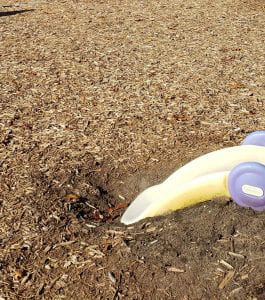 Bare soil on a playground near a small plastic slide